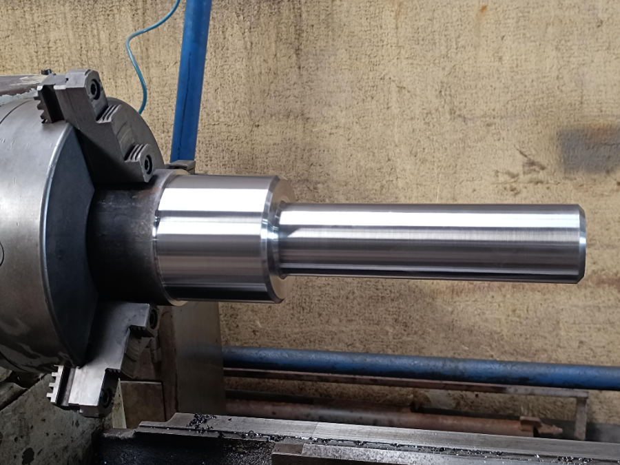 Eixo sendo usinado em torno mecânico industrial